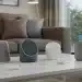 Smart home voice assistant devices including Alexa Echo, Google Nest, and Apple HomePod on a coffee table with smart lighting