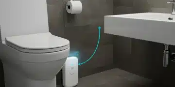 Smart water leak detector device connected to smartphone app in modern bathroom